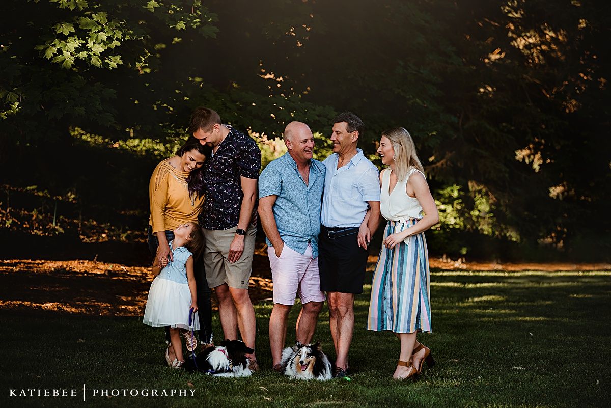 Group poses together for a casual portrait in a park with dappled afternoon sunlight.
