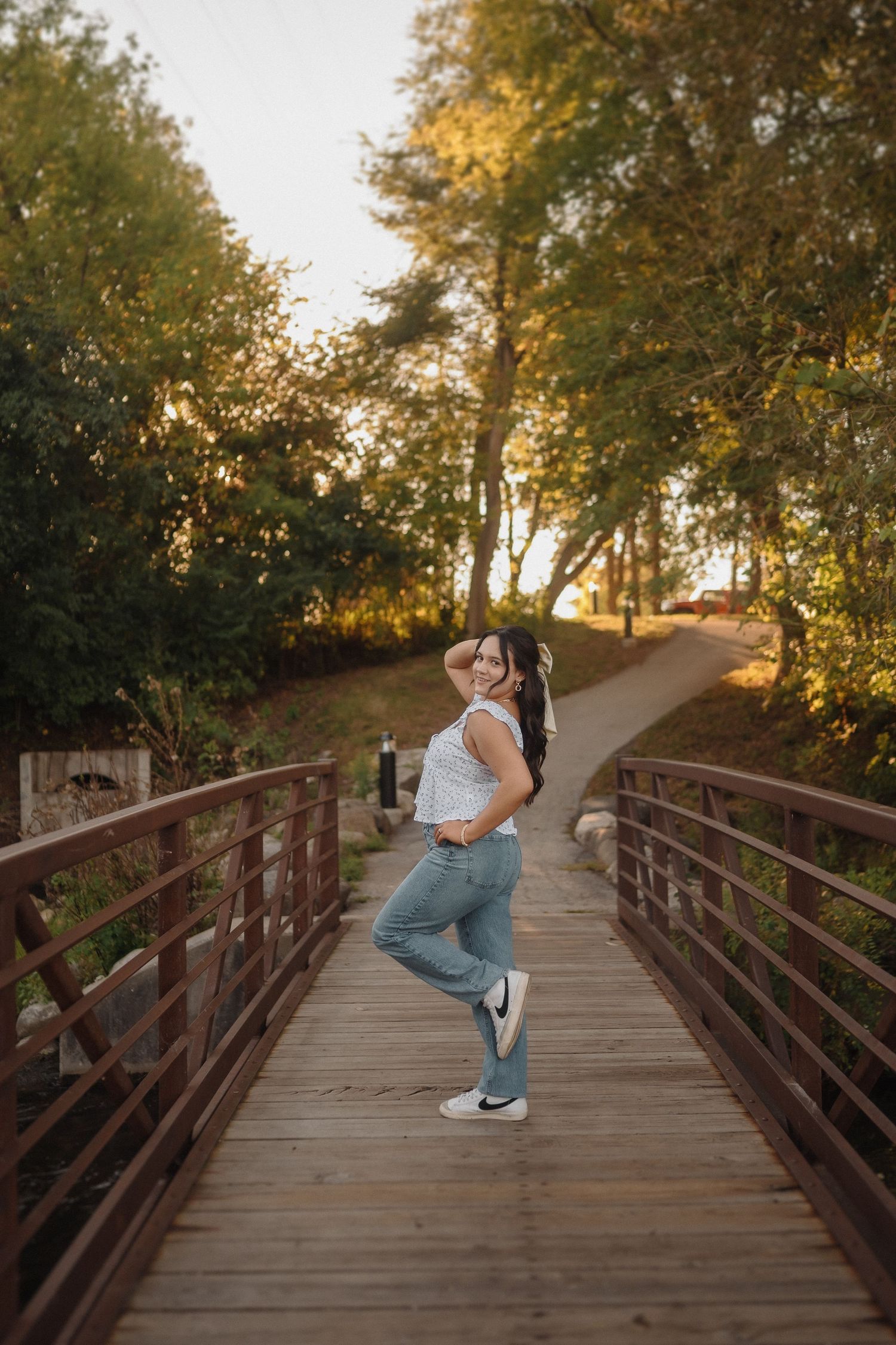 Playful portrait on wooden bridge with golden sunset light filtering through trees.