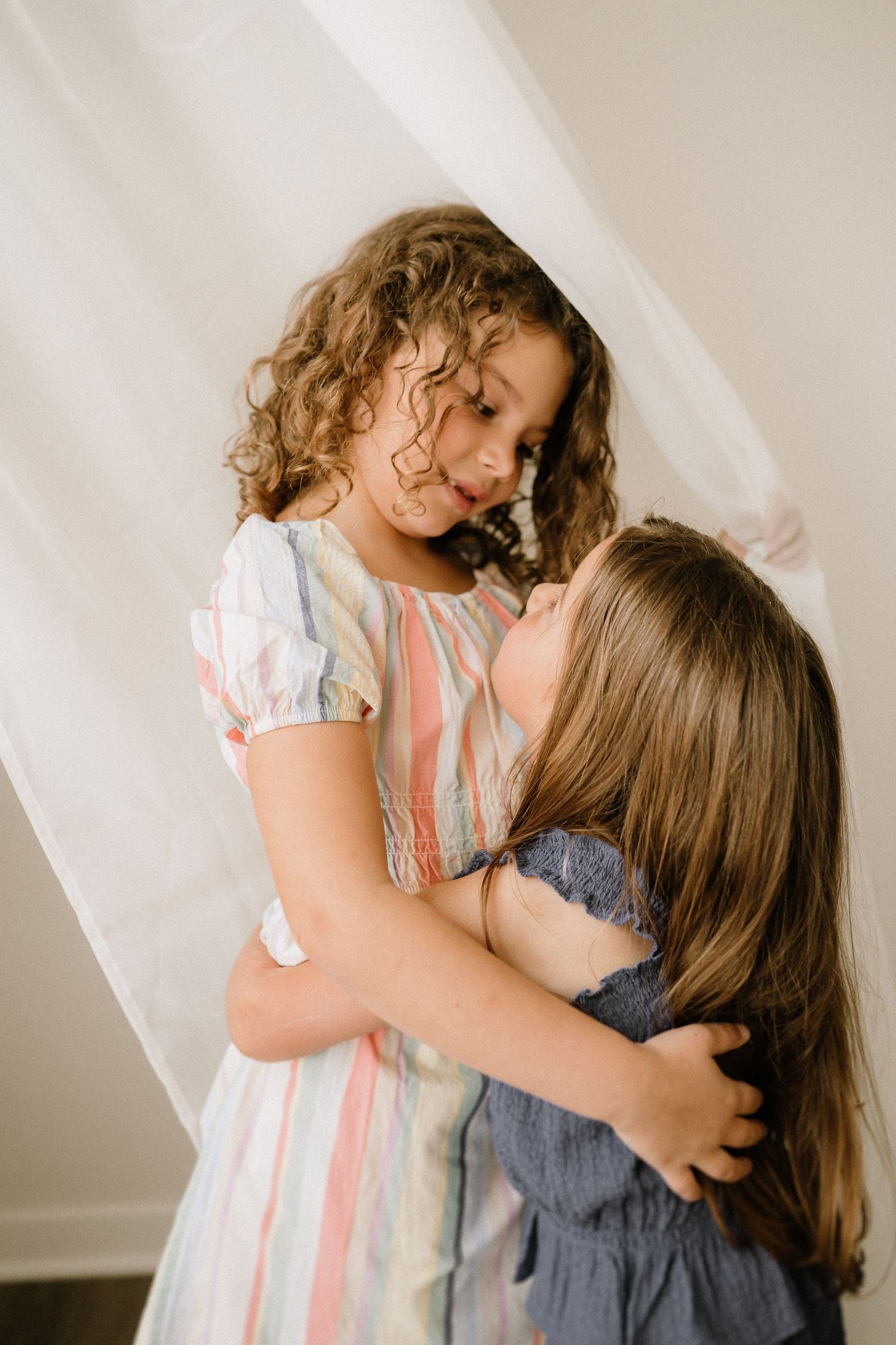 Two young people embrace each other in a tender moment against a light background.