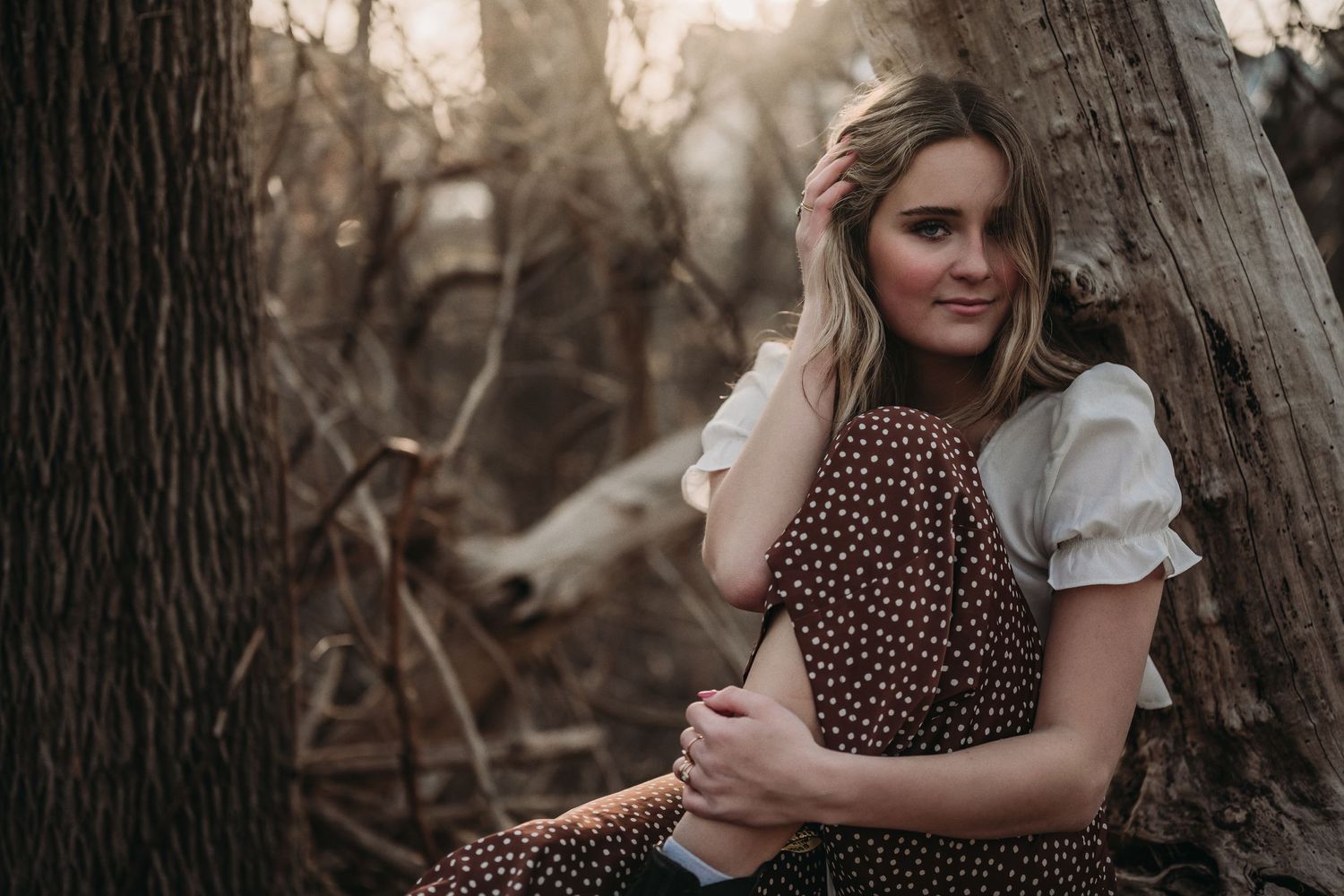 A vintage-inspired portrait featuring polka dot pants and white peasant top in a moody forest setting.