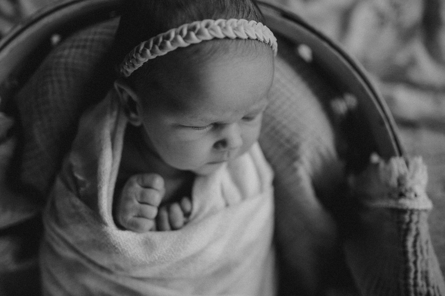Black and white portrait of sleeping infant wrapped in soft blanket wearing delicate headband.