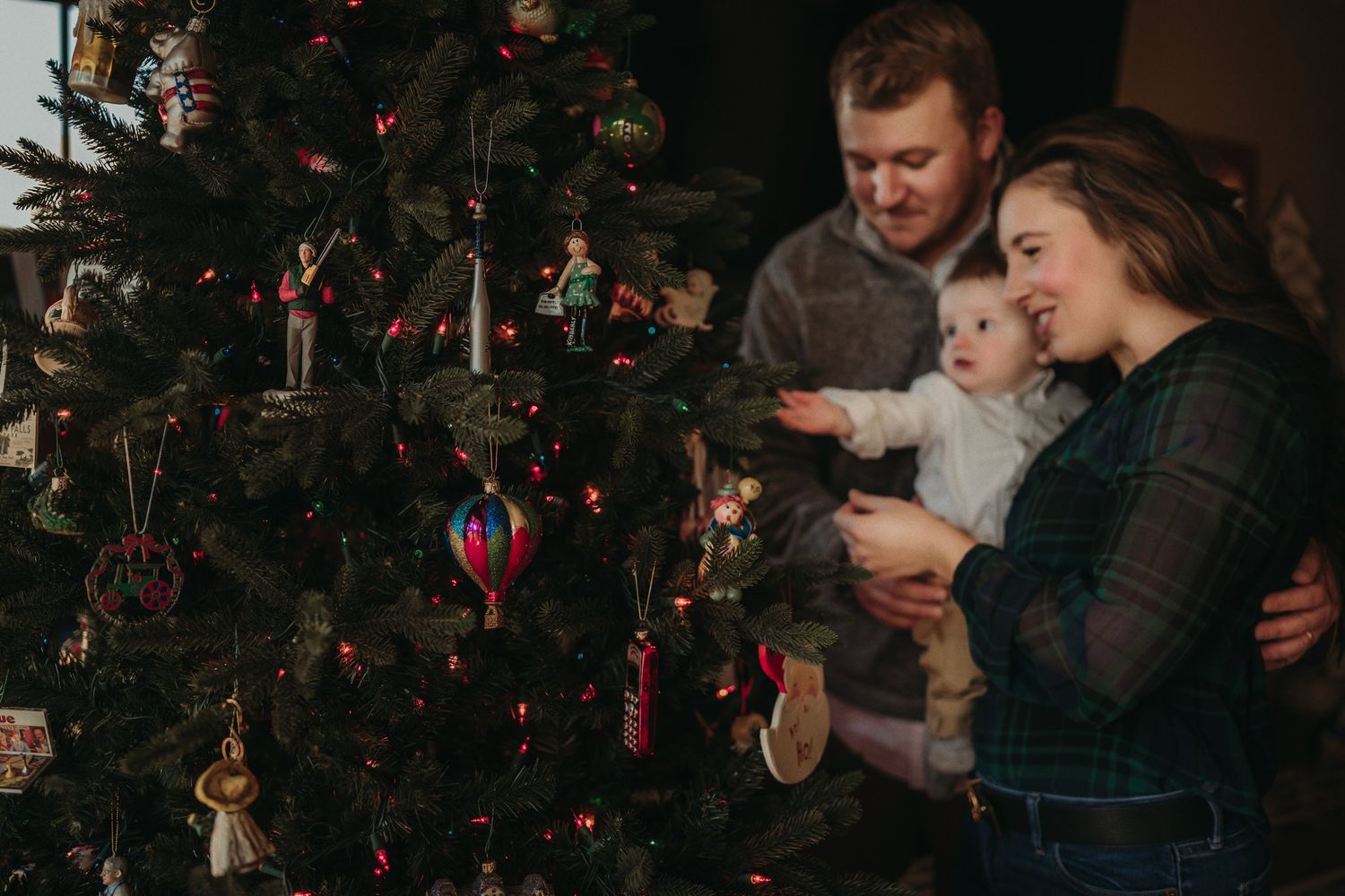 Family decorating their Christmas tree together in a warmly lit room.