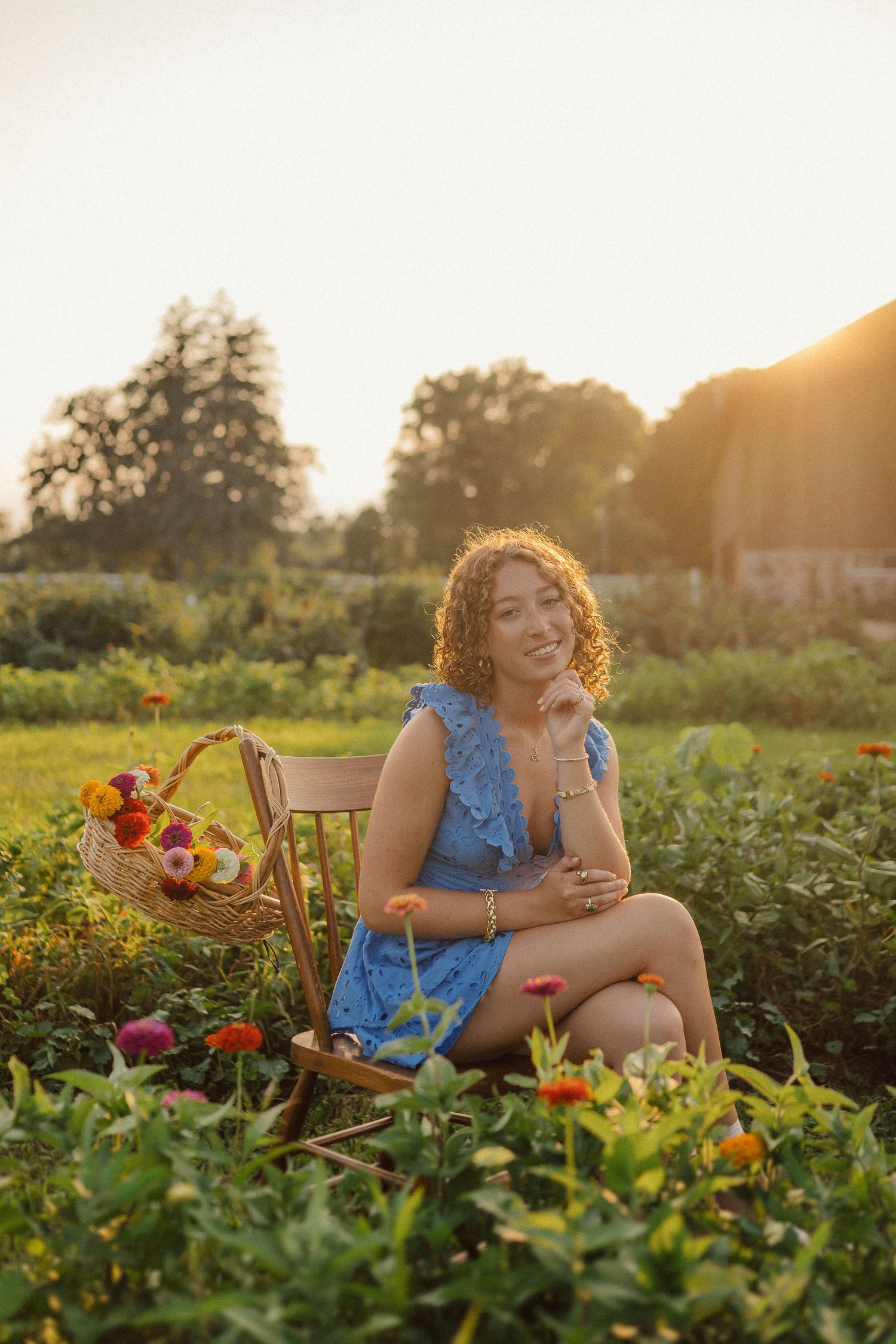 Woman sitting in garden field at golden hour picking flowers and enjoying fresh summer produce.