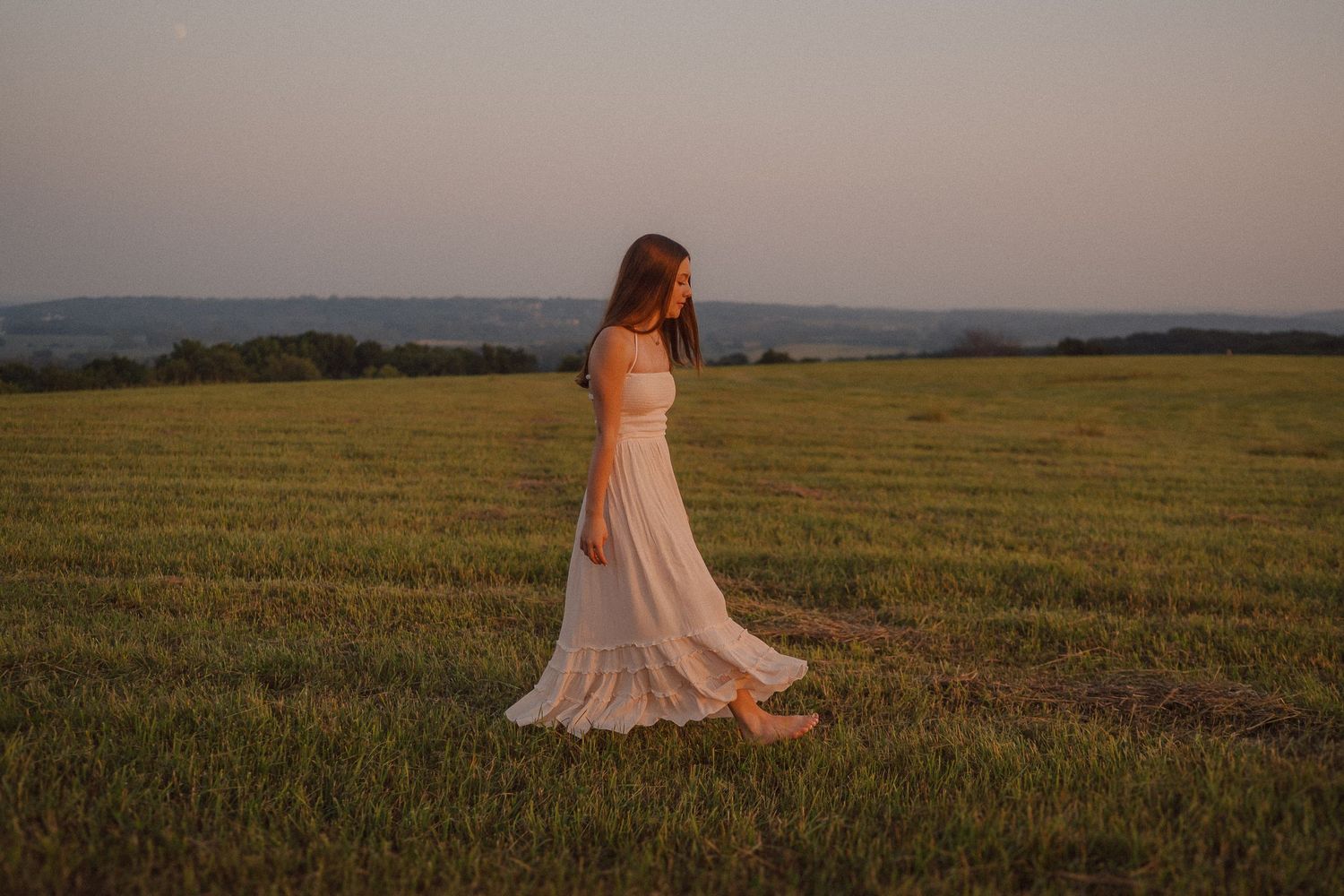 Person in flowing dress twirls gracefully in a golden meadow at sunset, creating a dreamlike silhouette.