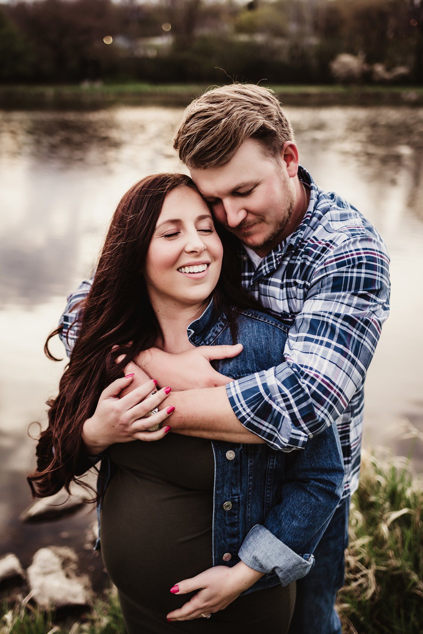 Sweet embrace by the lake during spring maternity photoshoot.