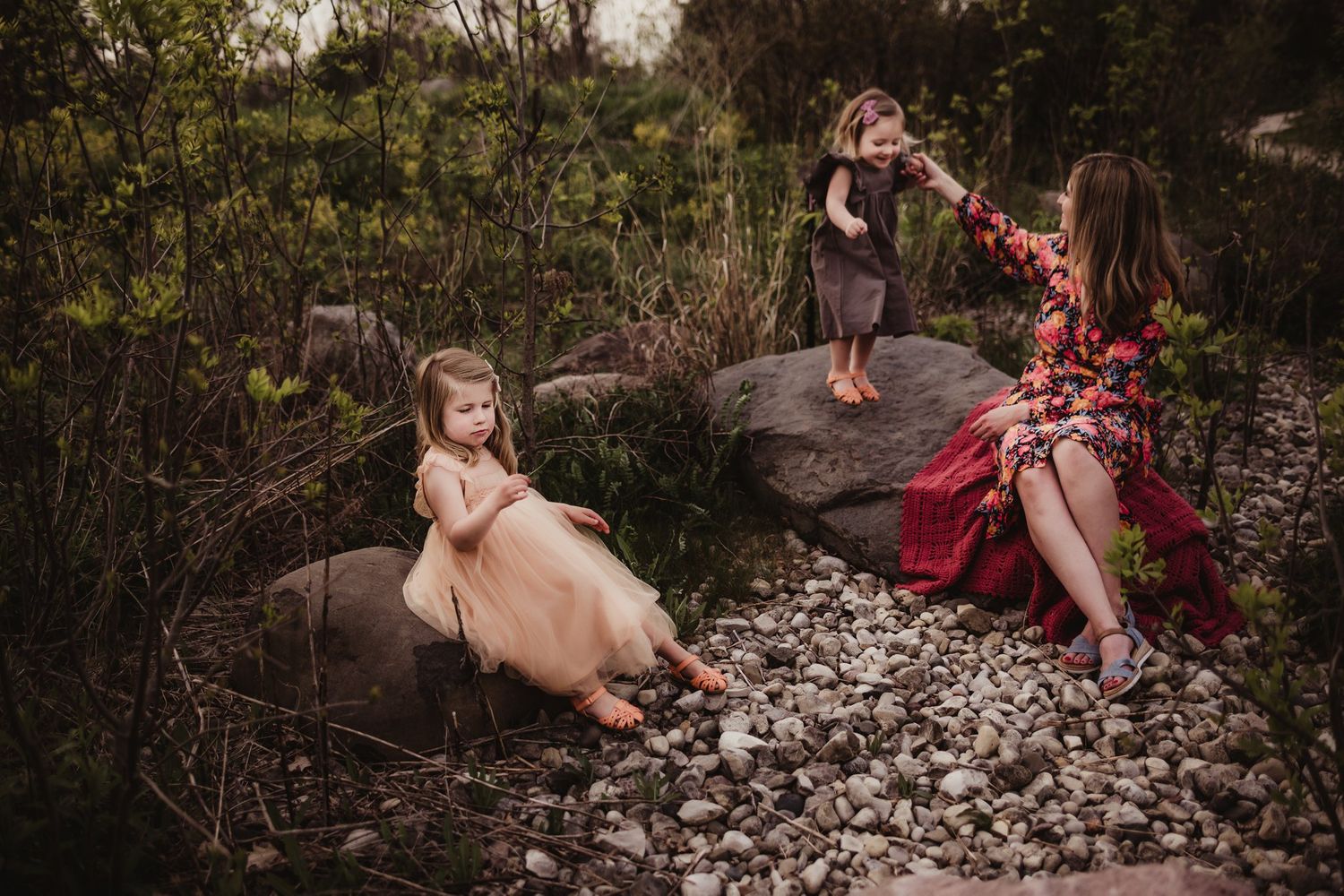 Relaxed outdoor family session with subjects posed on rocky terrain at sunset.