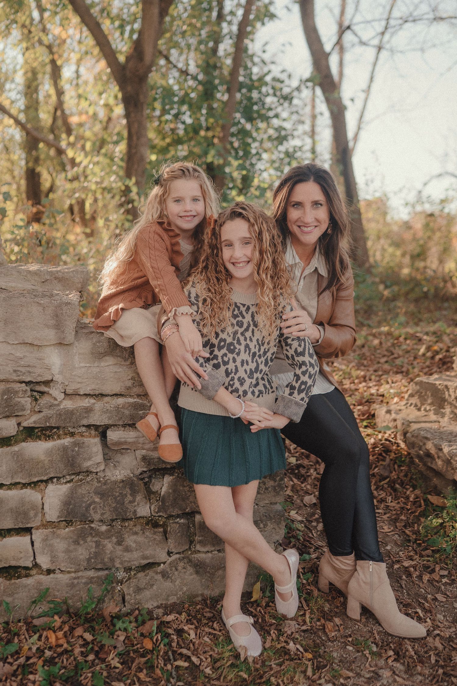 Candid family photos showing joyful moments together while sitting on a rustic stone wall outdoors.