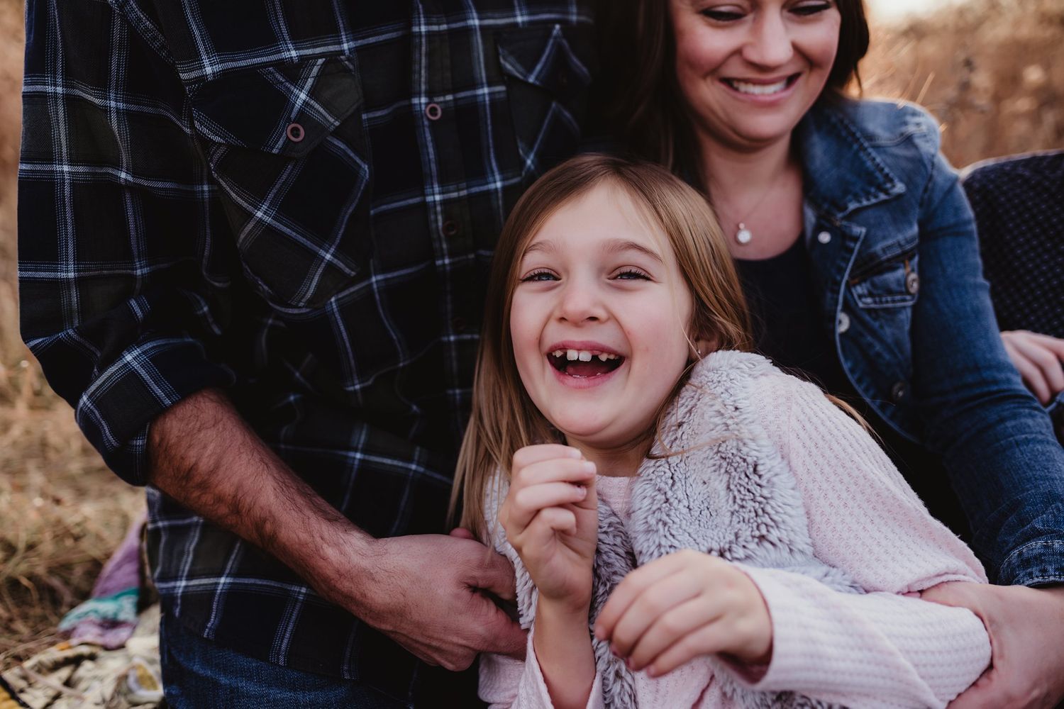 Family sharing candid laughter during outdoor photo session.