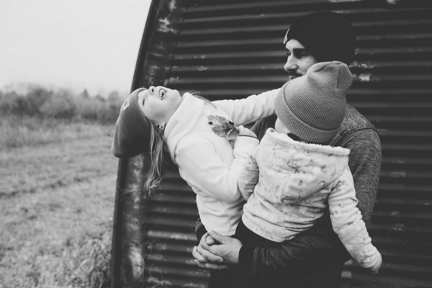 Black and white candid photo showing playful moment against metal structure.