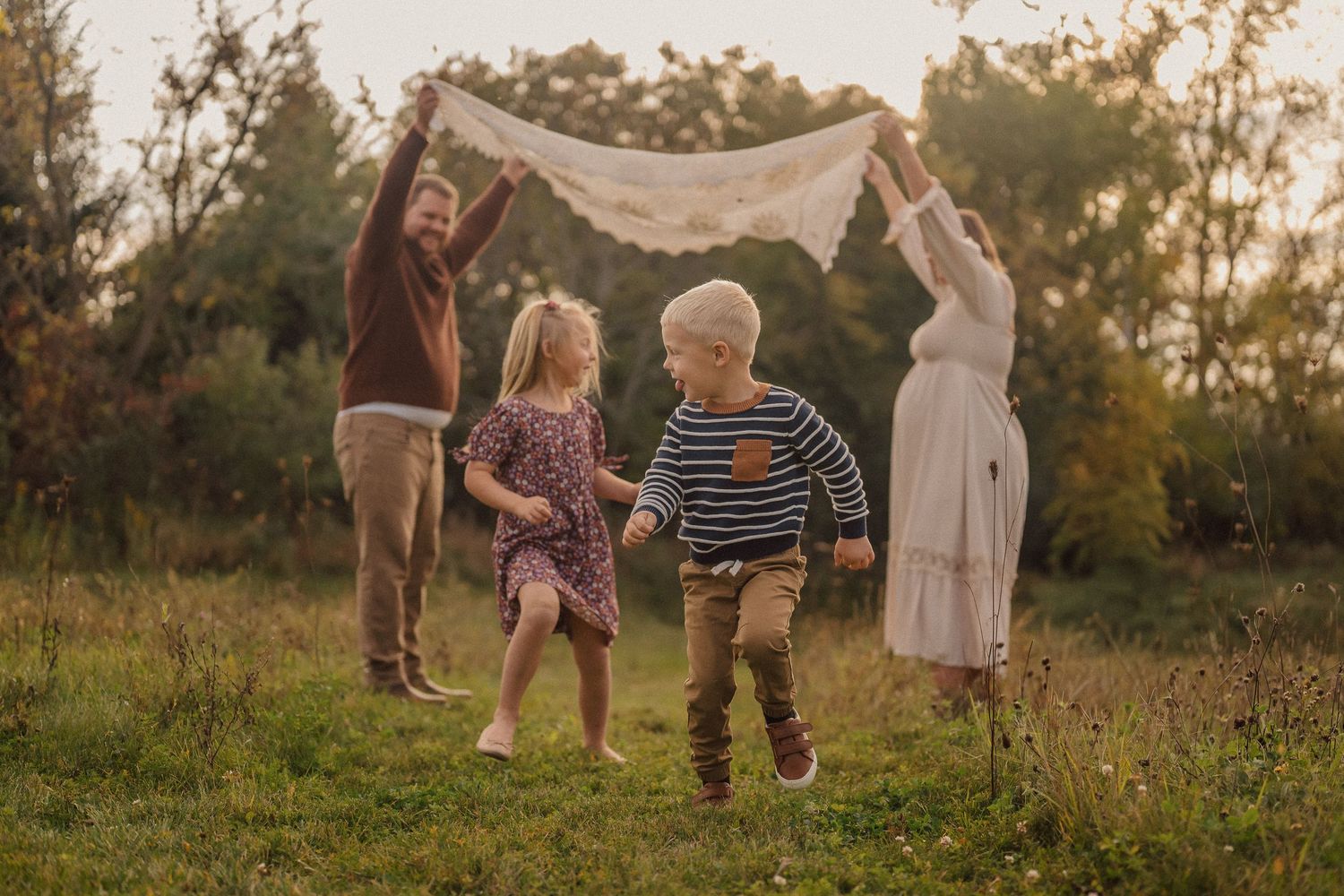 A group plays together in a golden sunlit field during sunset, creating joyful silhouettes against the warm sky.