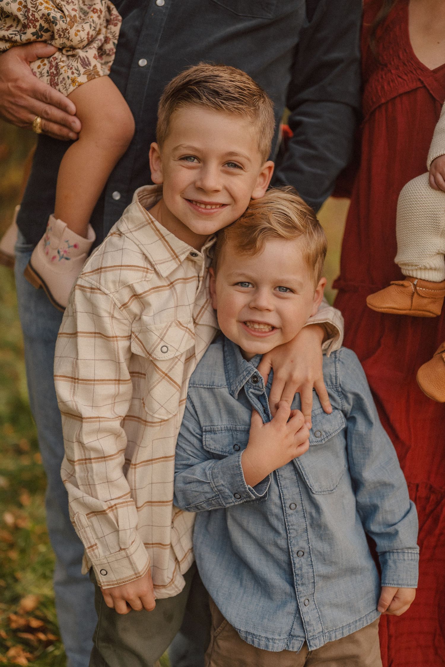 Two young children in coordinated outfits smile during outdoor autumn photoshoot.