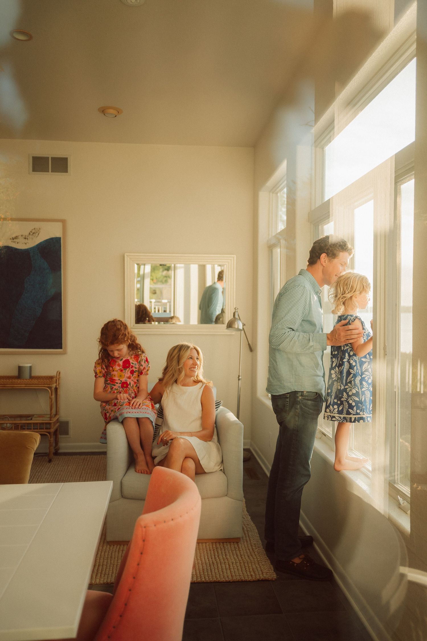 Casual interactions in a sunlit room with large windows and white furniture.