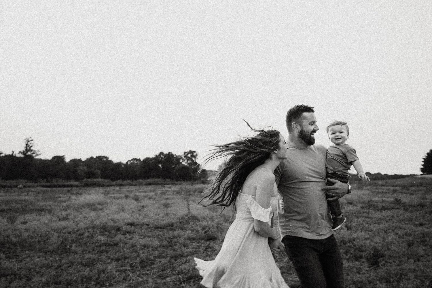 Black and white photo of a family running joyfully through a field.