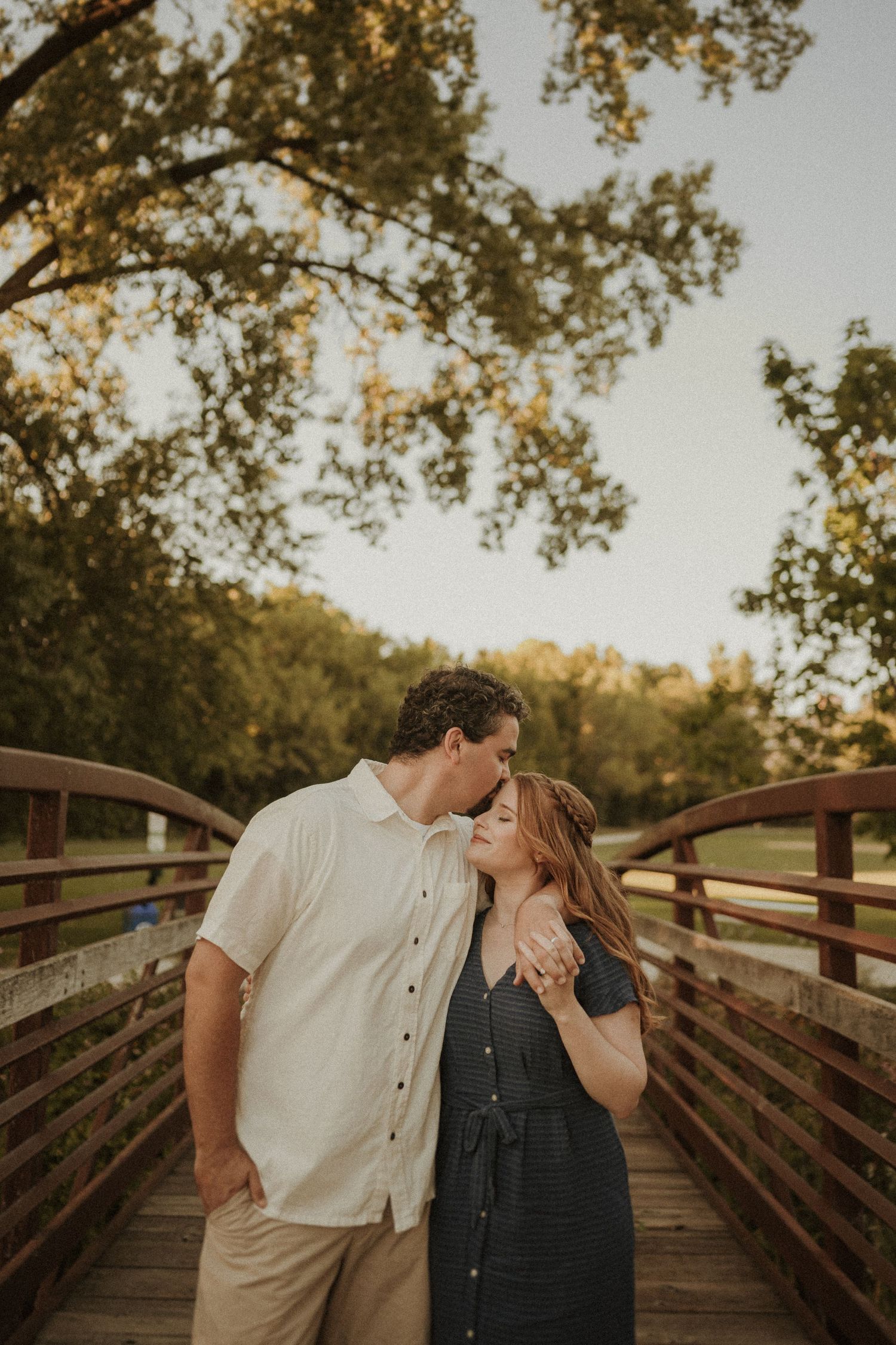 Romantic couple sharing an intimate moment on a wooden bridge during golden hour.