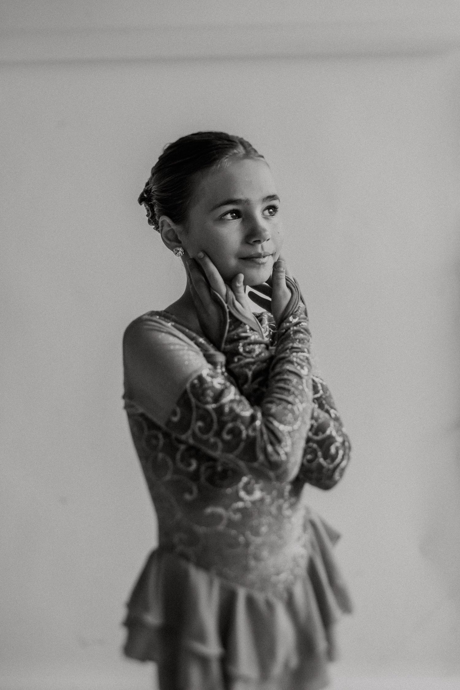 Black and white portrait of figure skater in performance attire striking elegant pose.