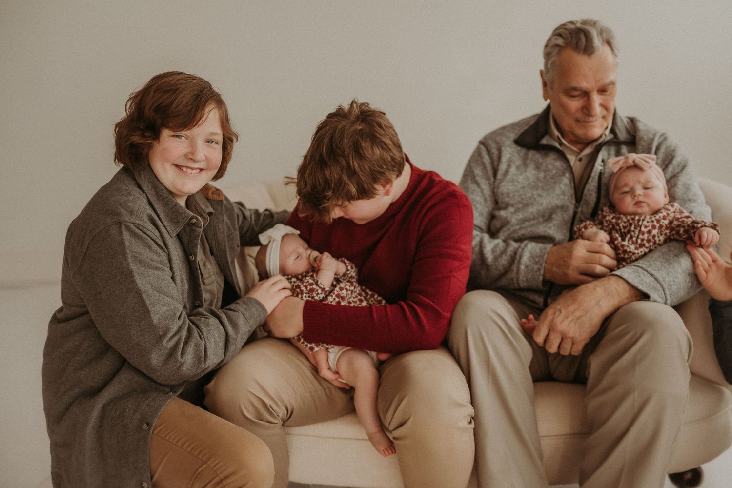 Family gathered on beige couch for indoor studio portrait session.