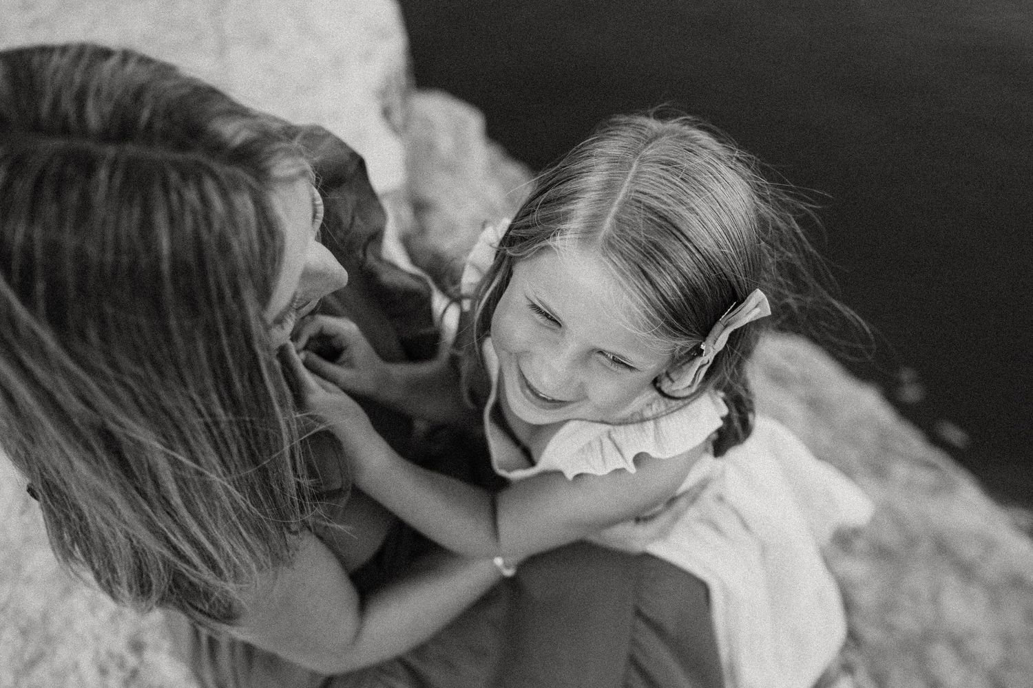 Black and white close-up photograph showing a sweet interaction on stone steps outdoors.