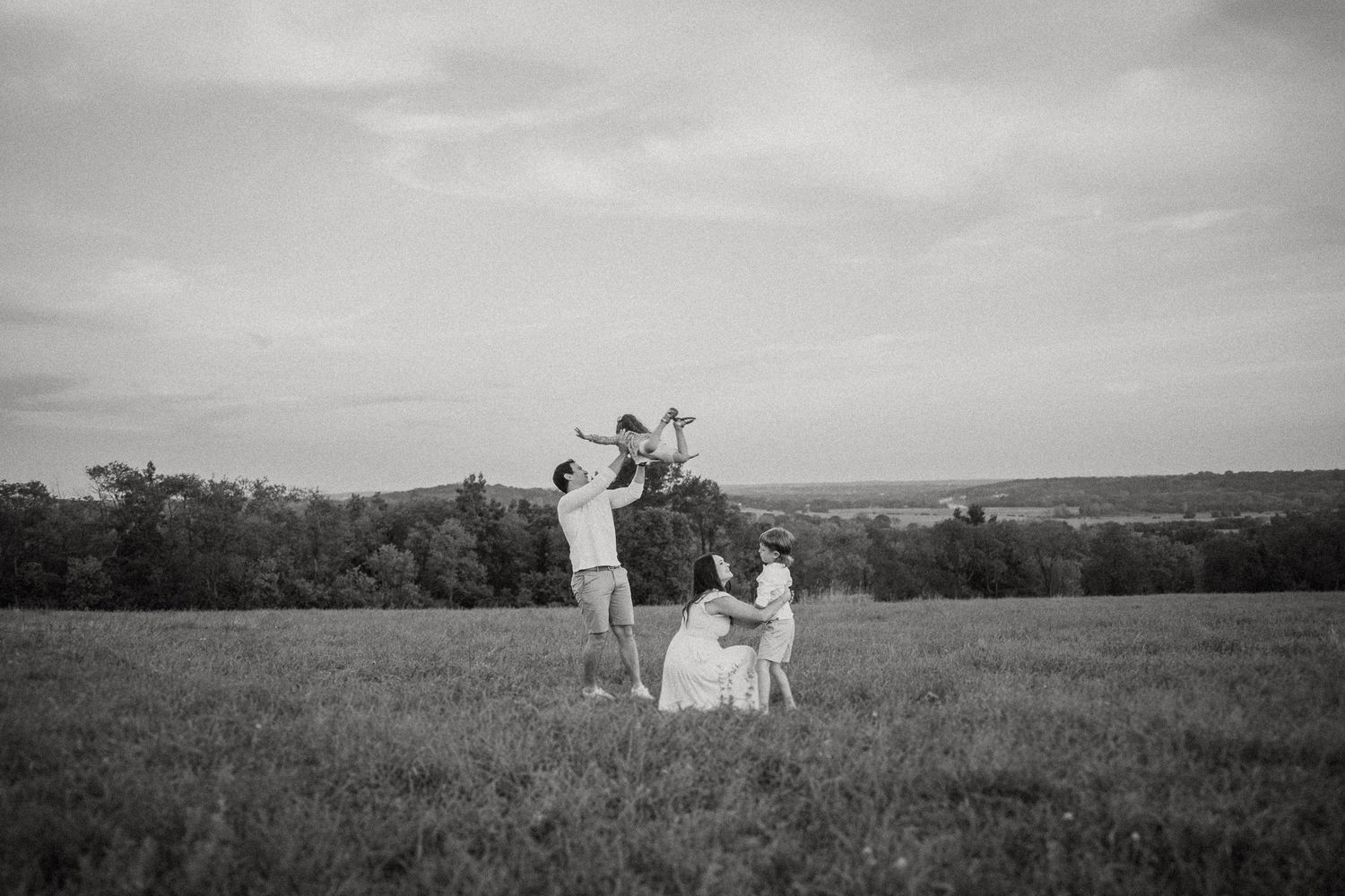 Black and white photo of a family dancing together in an open field.