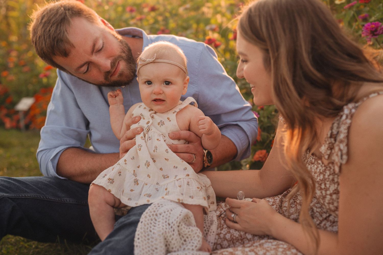 Golden hour family moment in garden with colorful zinnias blooming in background.