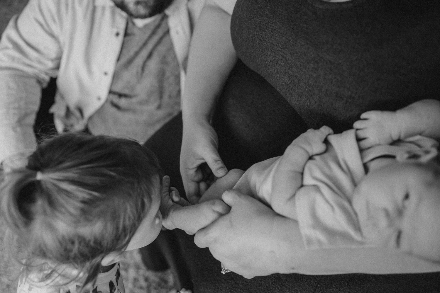 Black and white image of family members gathered around a sleeping infant.