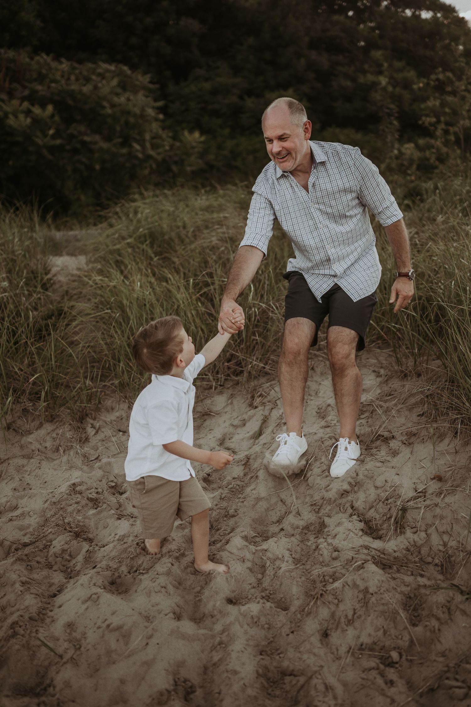 A joyful moment of two people jumping on sandy dunes during golden hour.