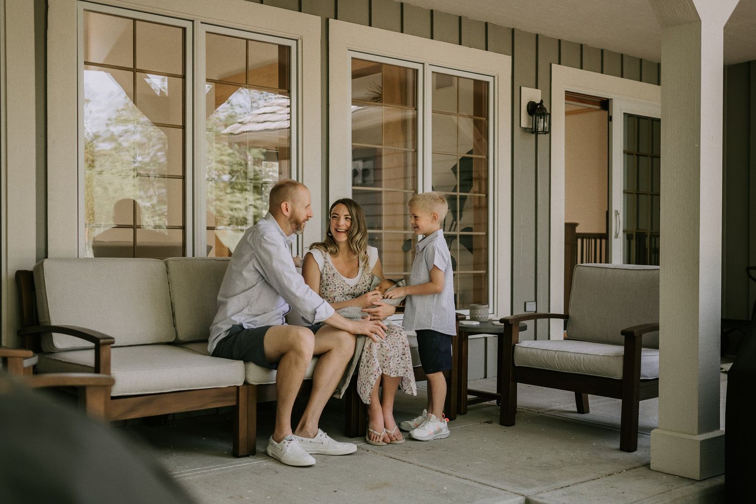 Family spending time together on a bright sunlit front porch with white columns.