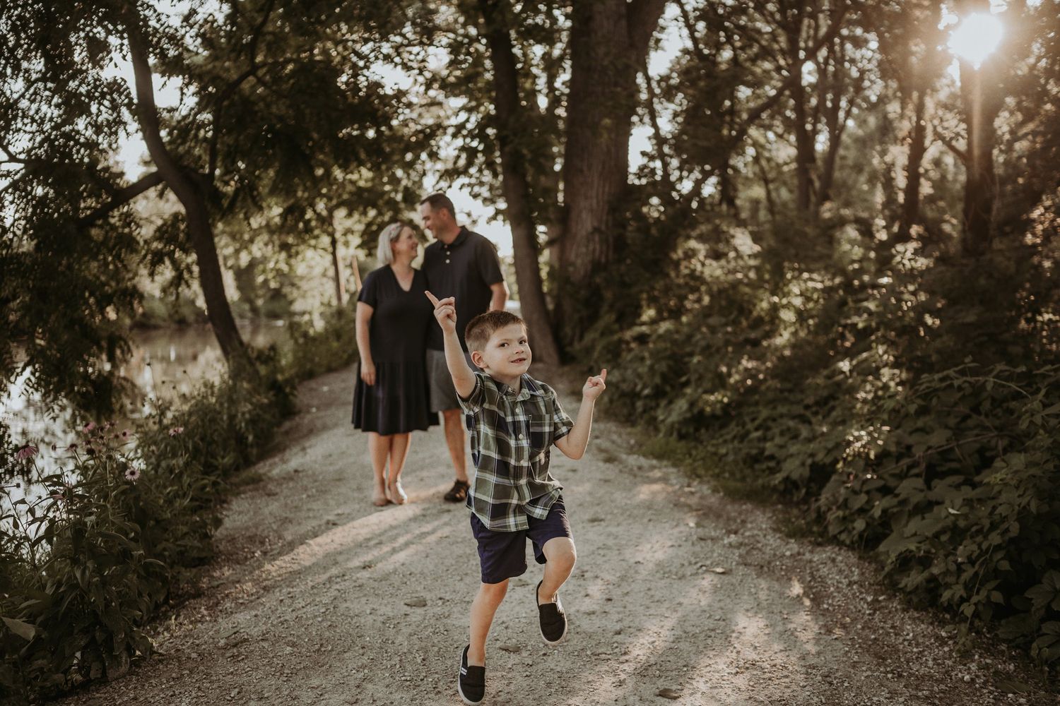 Child running ahead on a sunlit path while adults follow behind.