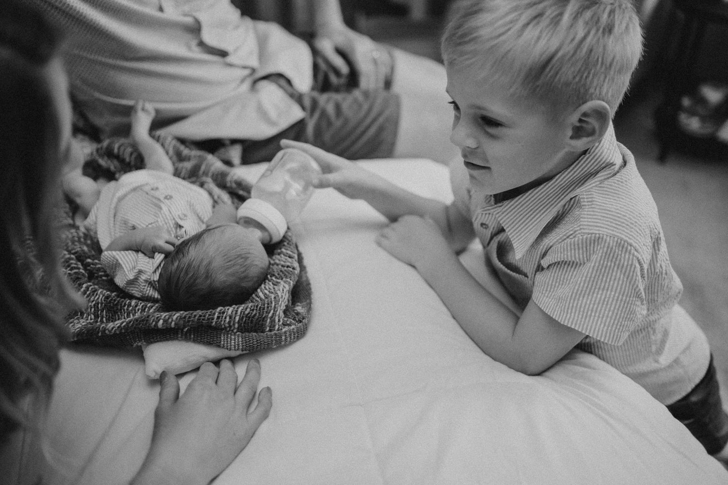A black and white photo capturing a heartwarming family moment with a newborn.