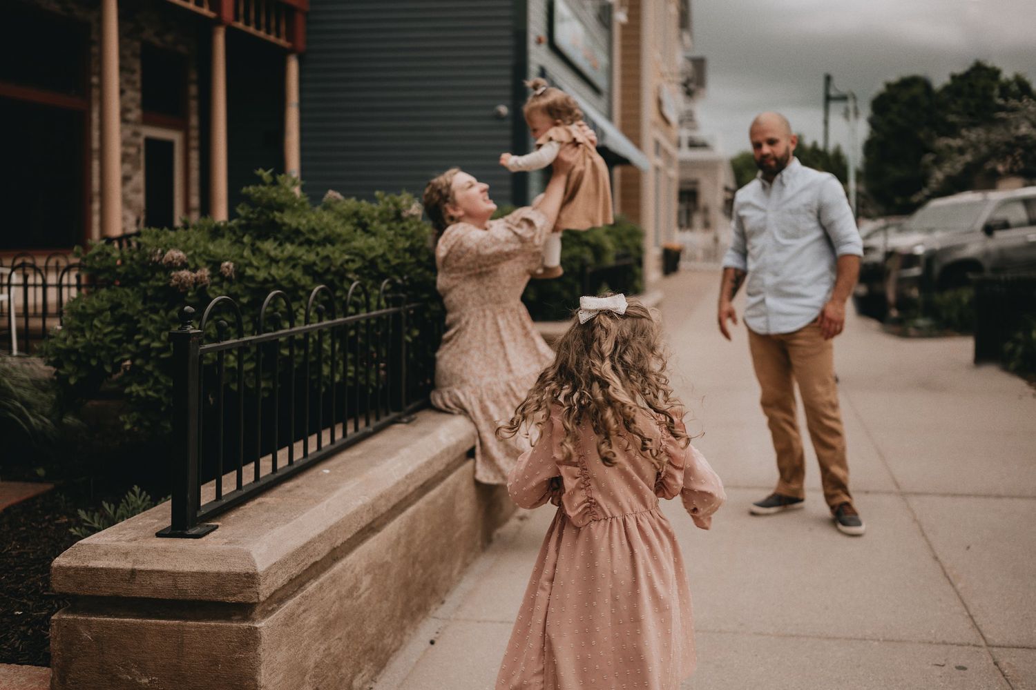 A candid family moment captured on an urban sidewalk with warm lighting.