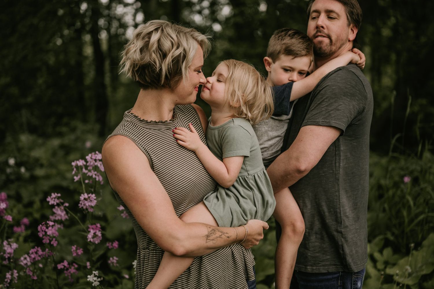 Intimate family moment captured in a garden with purple flowers blooming in background.
