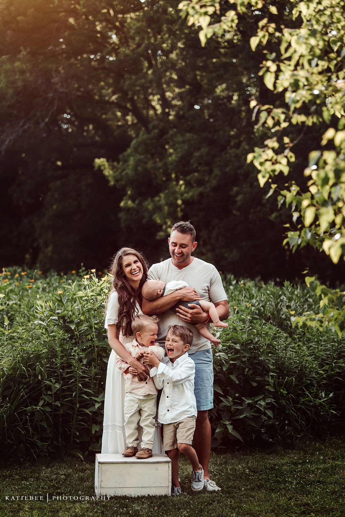 Joyful family portrait outdoors with someone standing on a wooden box.