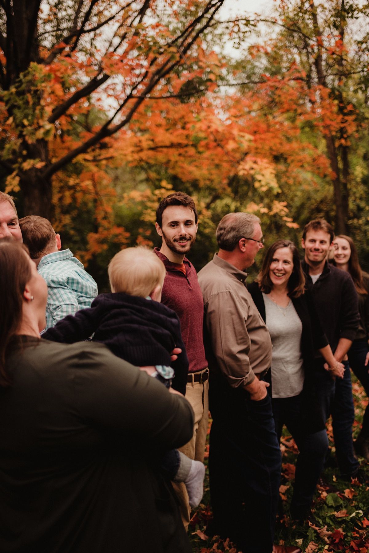 Group gathered together for outdoor family photos surrounded by fall foliage.