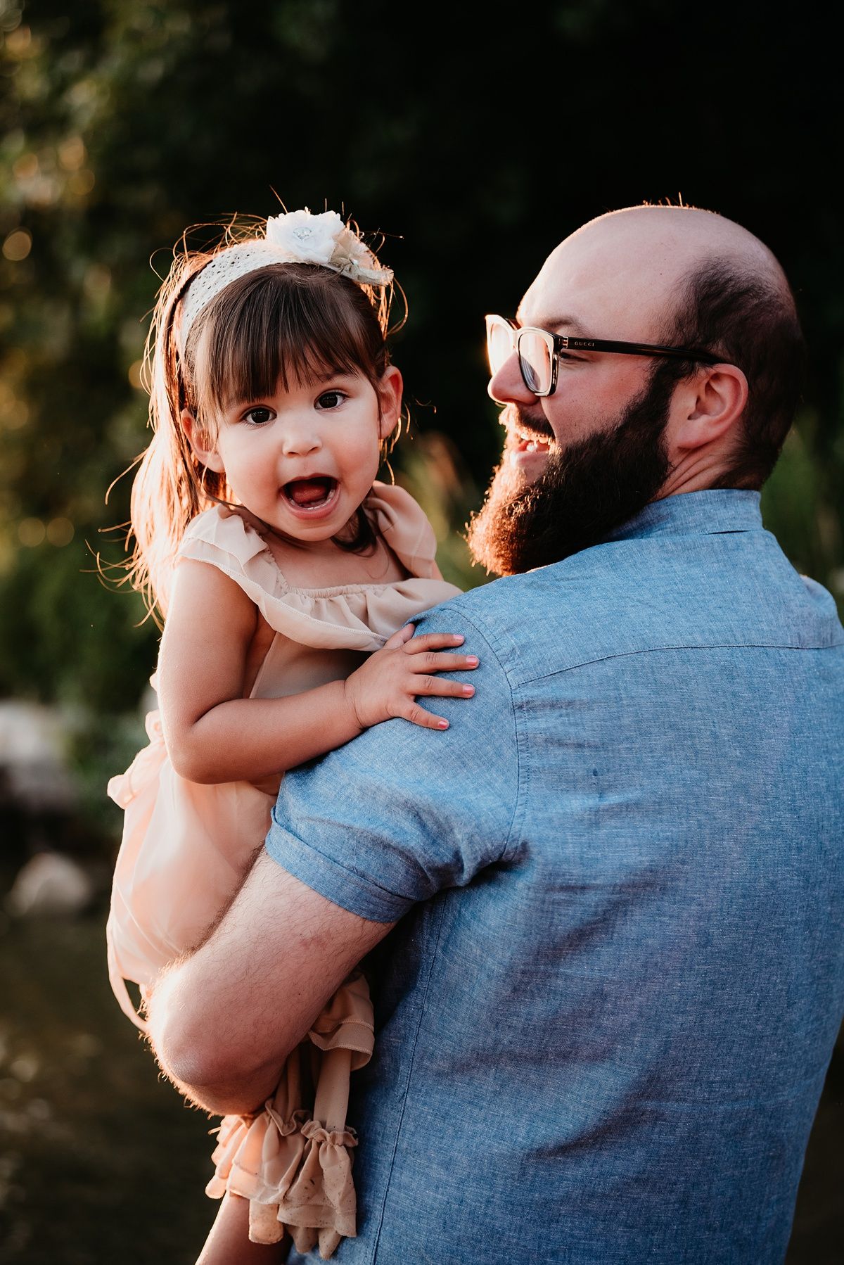 Candid outdoor portrait of joyful parent-child moment in warm sunlight.