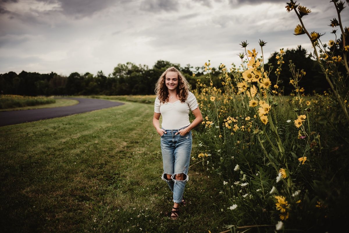 Casual outdoor portrait in a field with blooming yellow flowers along a curved path.