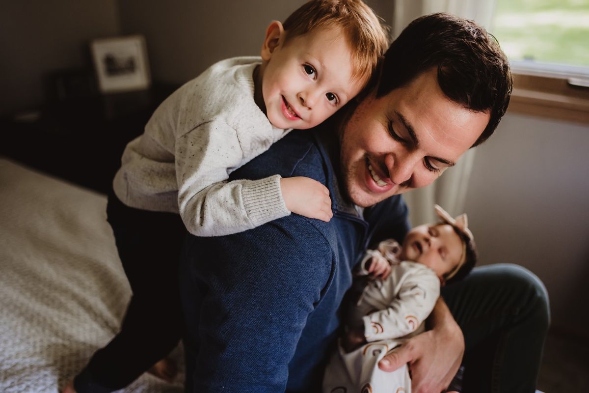 Joyful indoor family moment with playful expressions and laughter on a cozy bed.