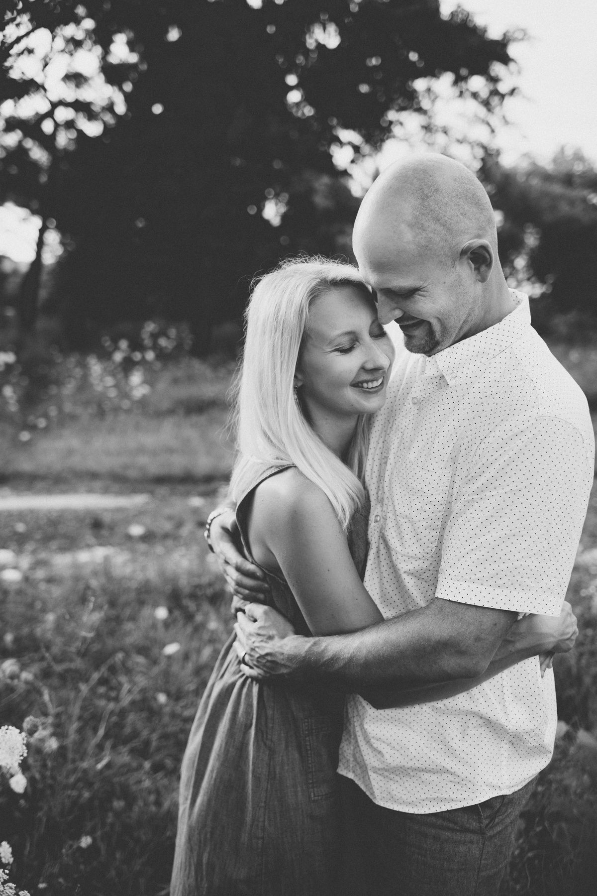 Black and white portrait of a couple sharing an intimate moment outdoors.