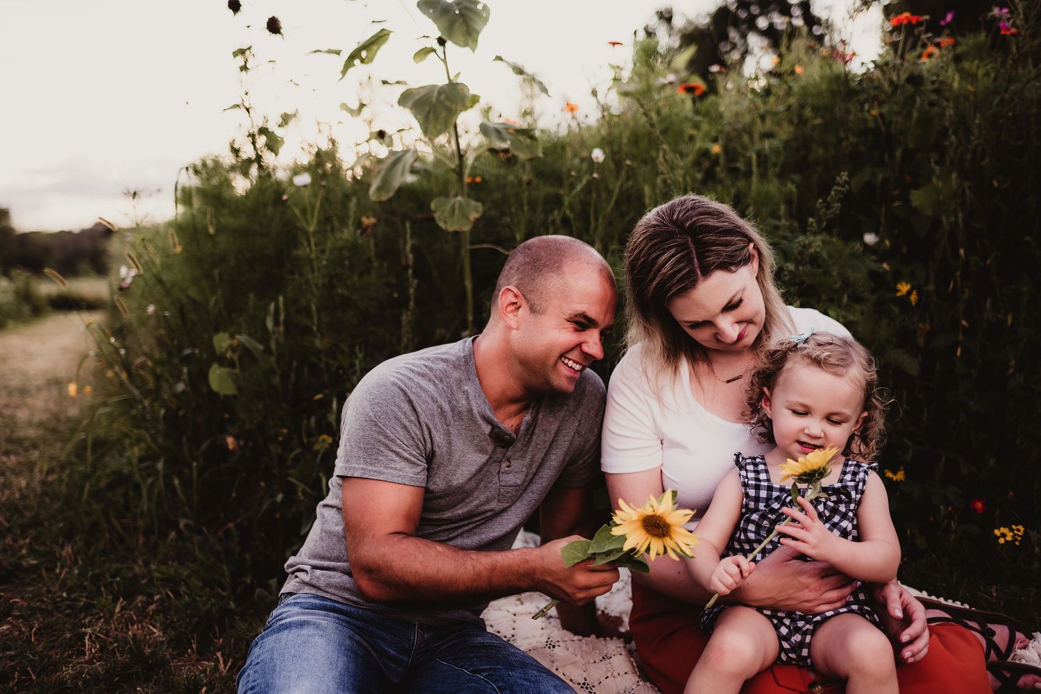 A family shares joyful moments together in a garden setting at sunset.