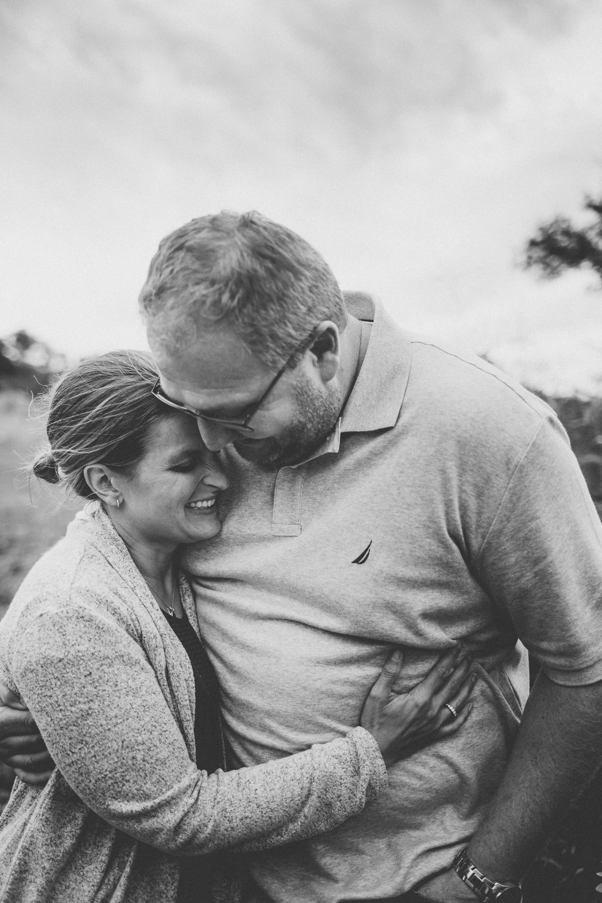 A tender black and white moment captured between a couple embracing outdoors.