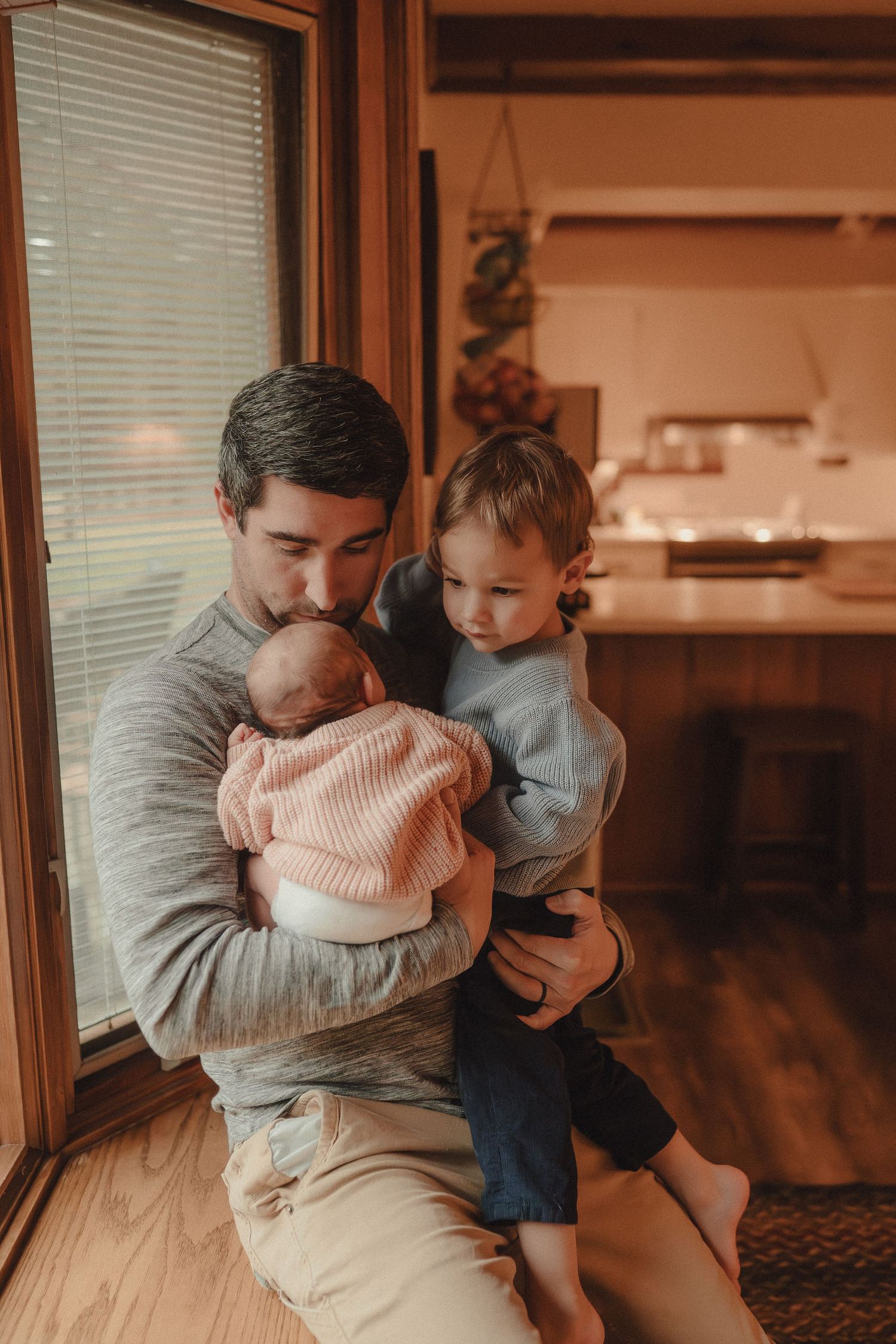 Warm-toned photo sequence capturing tender moments by a window with venetian blinds.