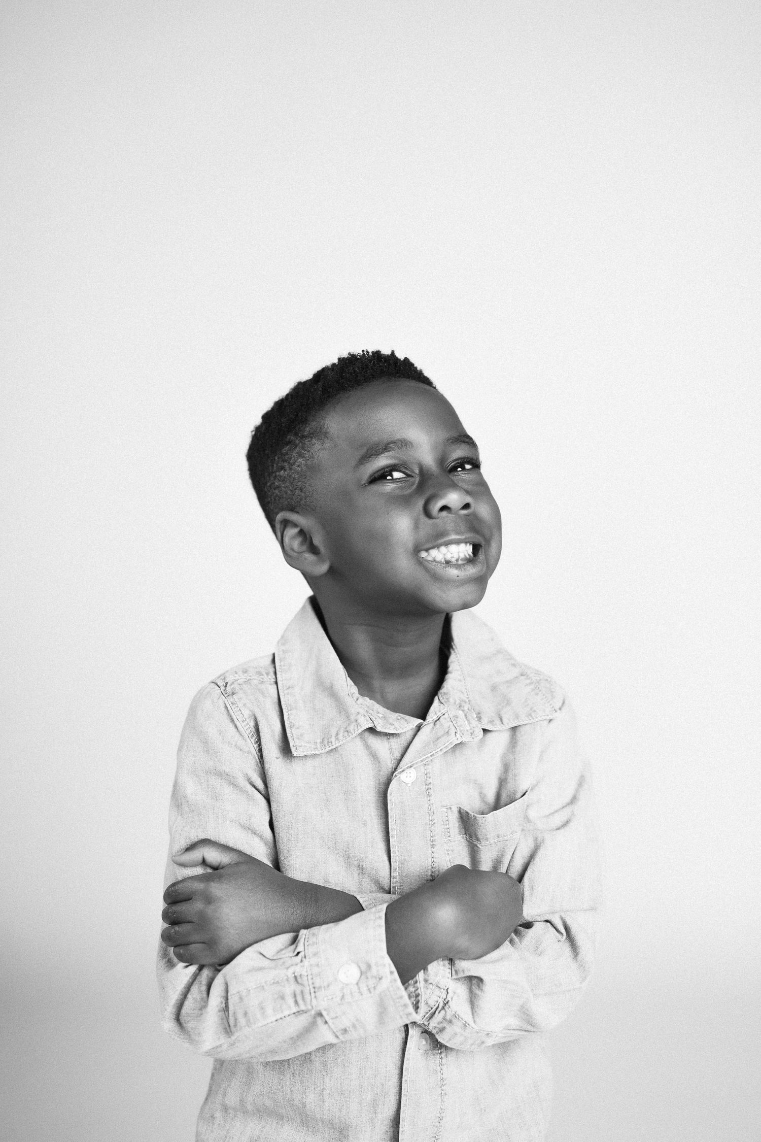 A child in a white button-up shirt shows joyful expressions in a series of black and white portrait photos.