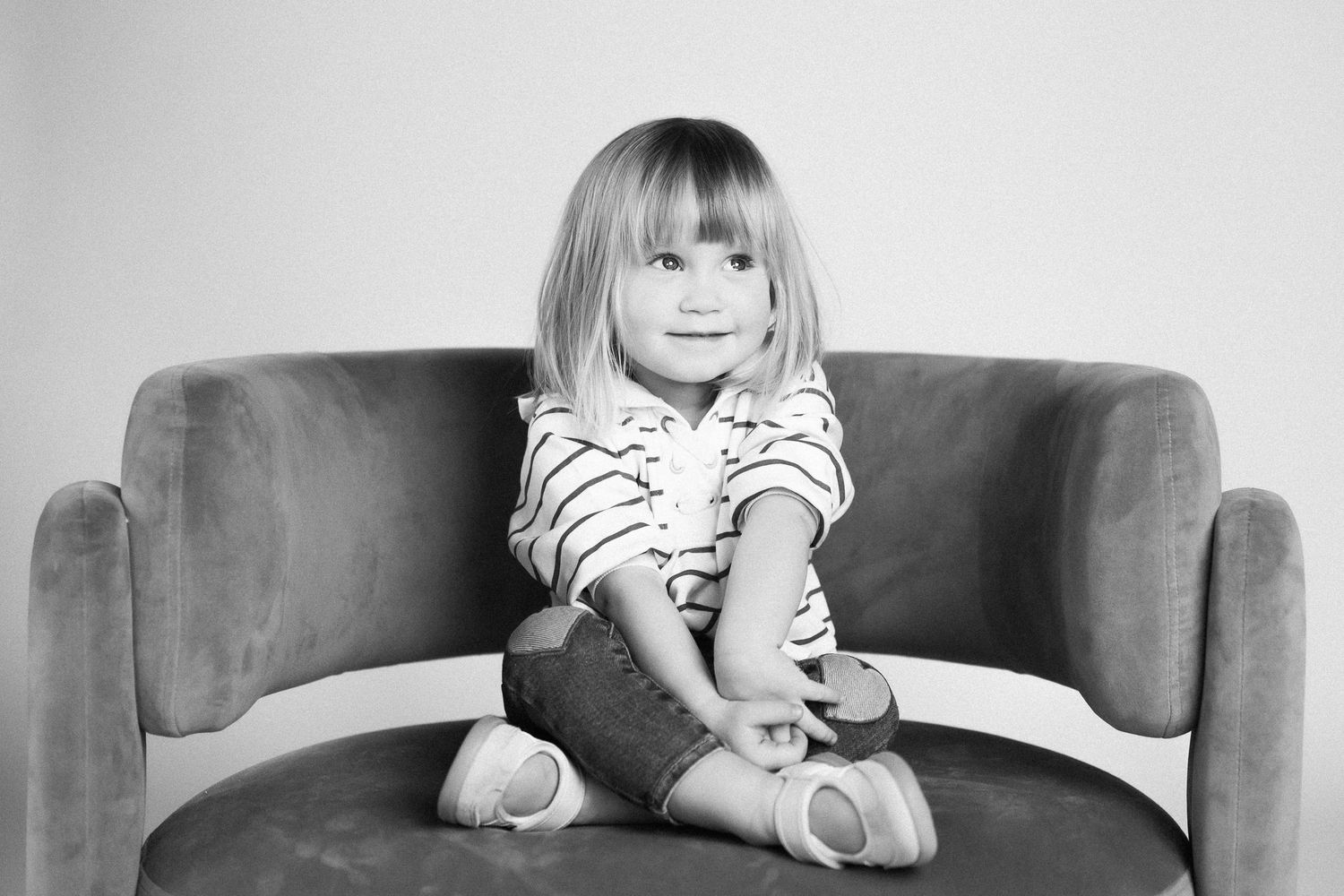 A sequence of four black and white photos shows a child sitting on a couch in different casual poses.