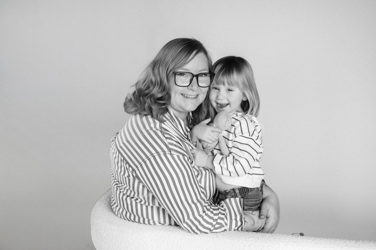A black and white photo series shows intimate moments between two people wearing striped shirts against a light background.