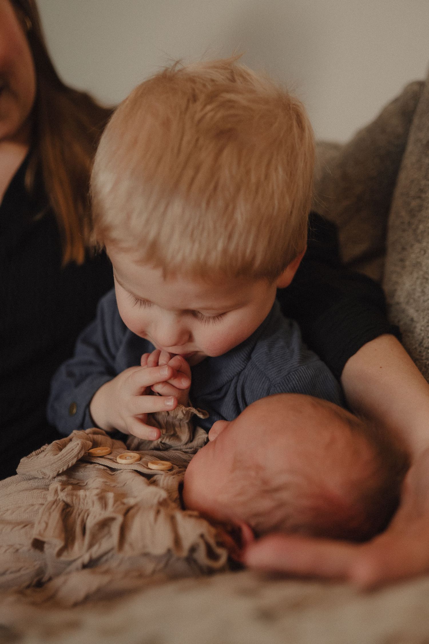 Intimate sequence showing a child gently interacting with a baby on a couch.