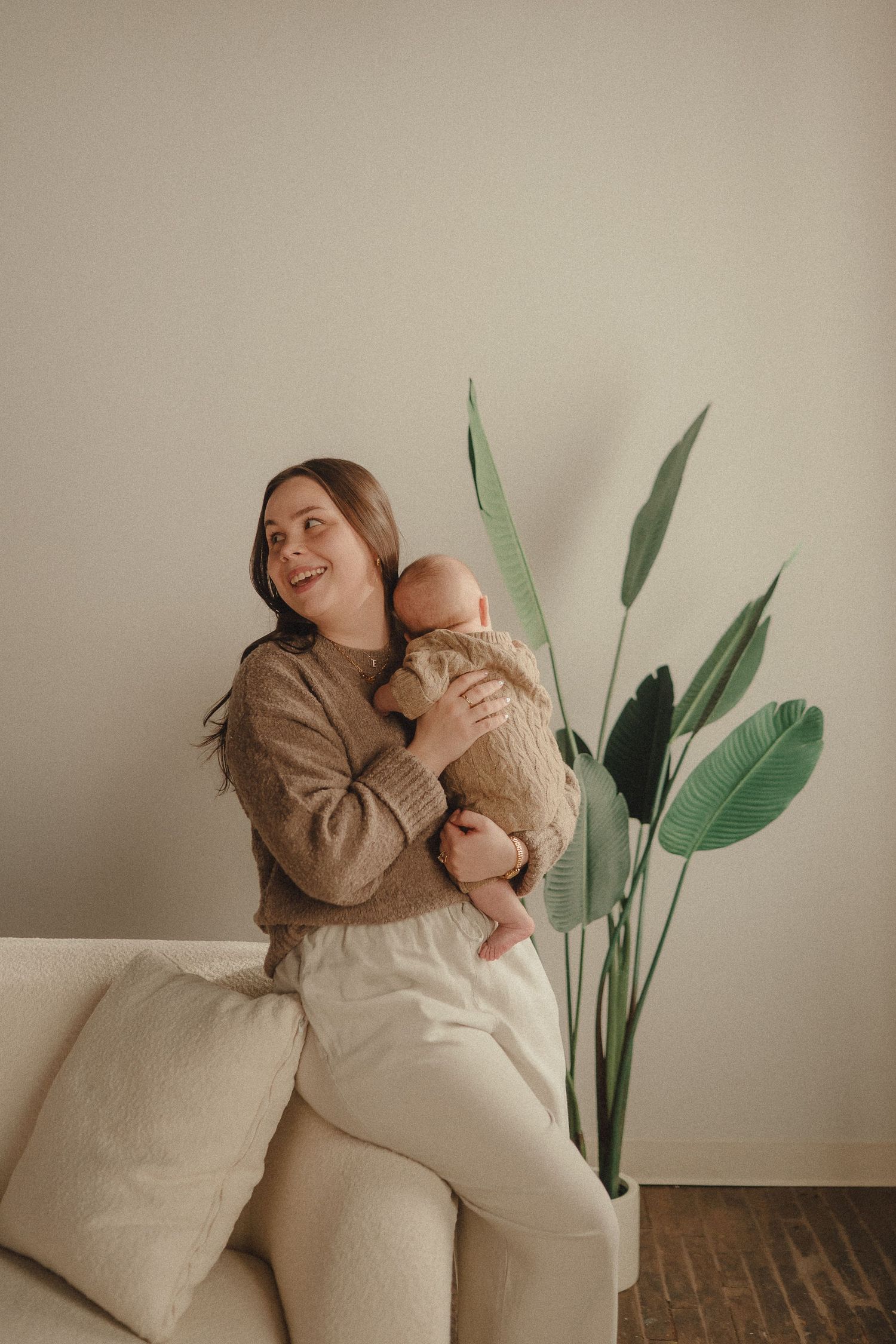 Intimate family portrait session in neutral tones with a potted plant in the background.