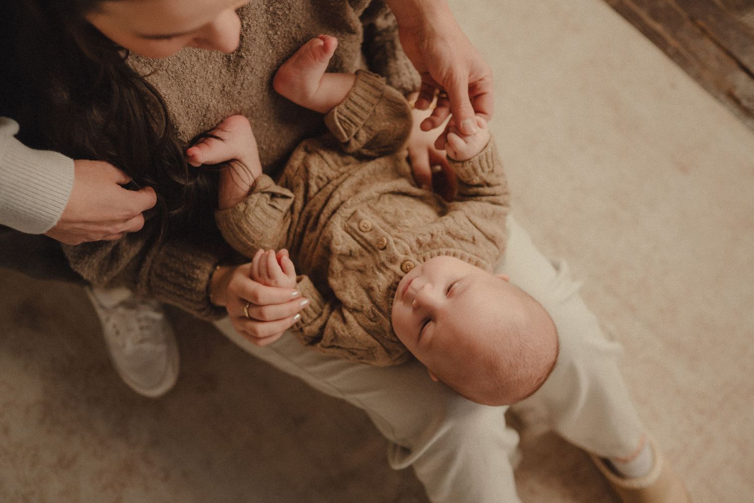 Hands gently massage a baby's feet during a tender newborn care session.