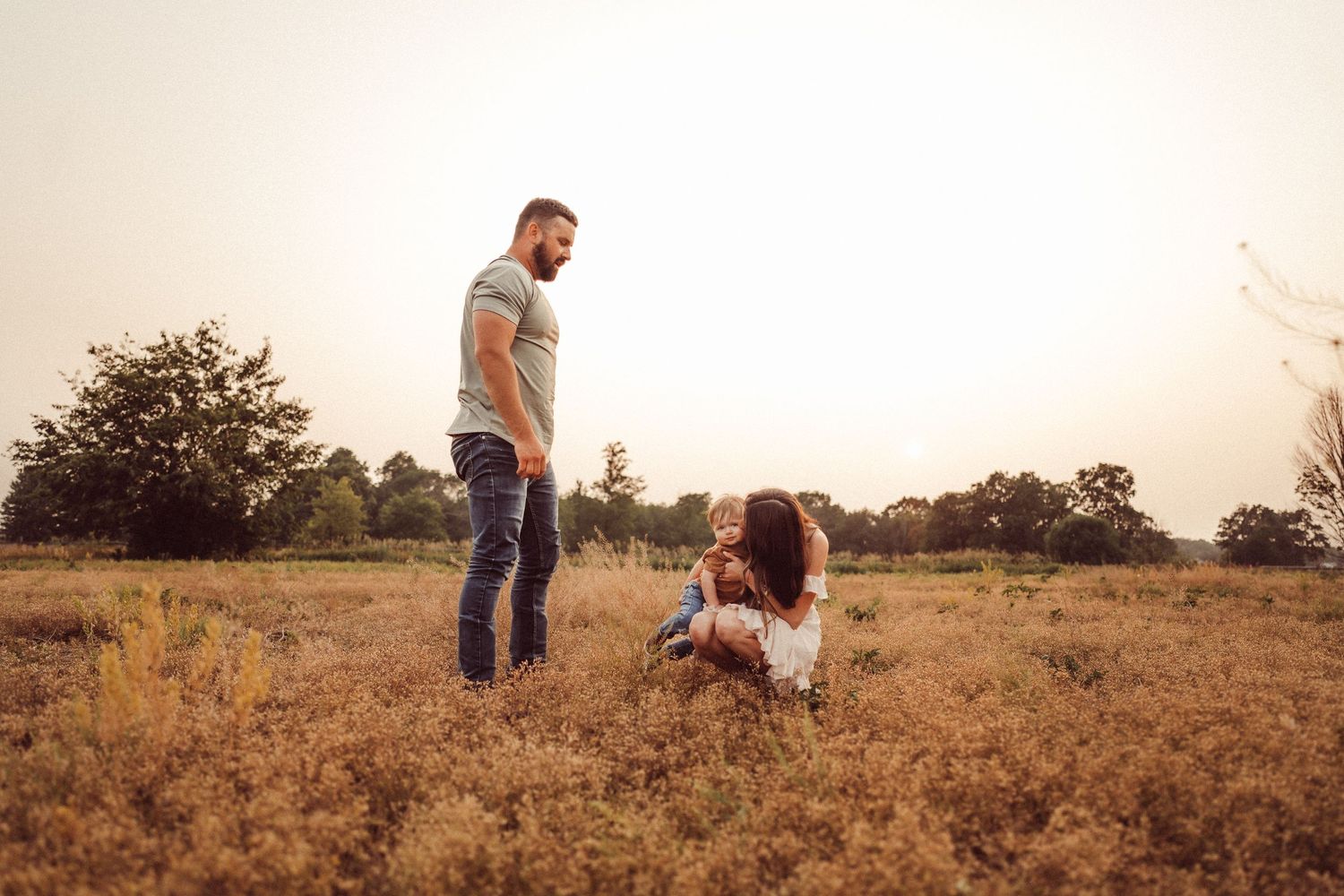 Family enjoying a sunset moment together in a golden wheat field.