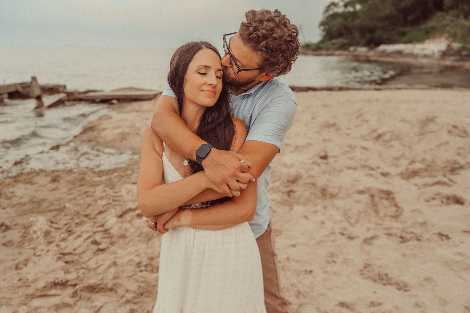 Intimate beach portrait with warm sunset lighting and coastal scenery.