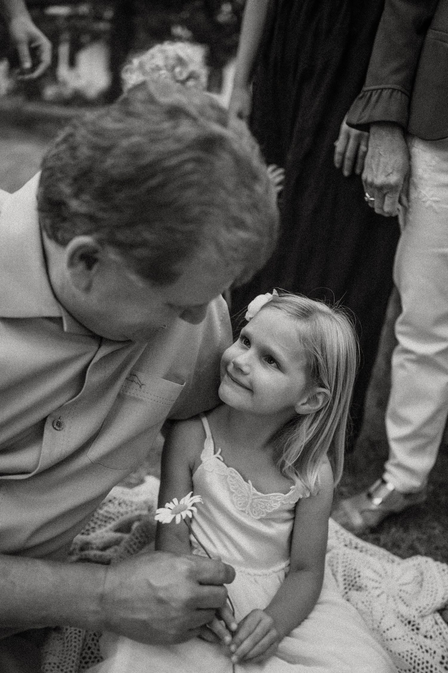 Black and white candid moment between two people during outdoor gathering.