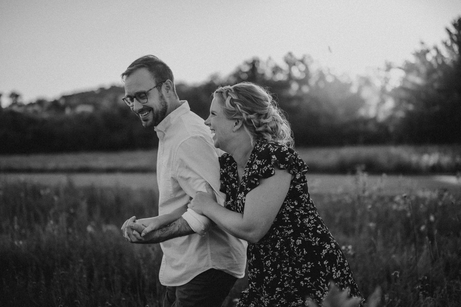 Joyful couple laughing together in black and white photo outdoors.