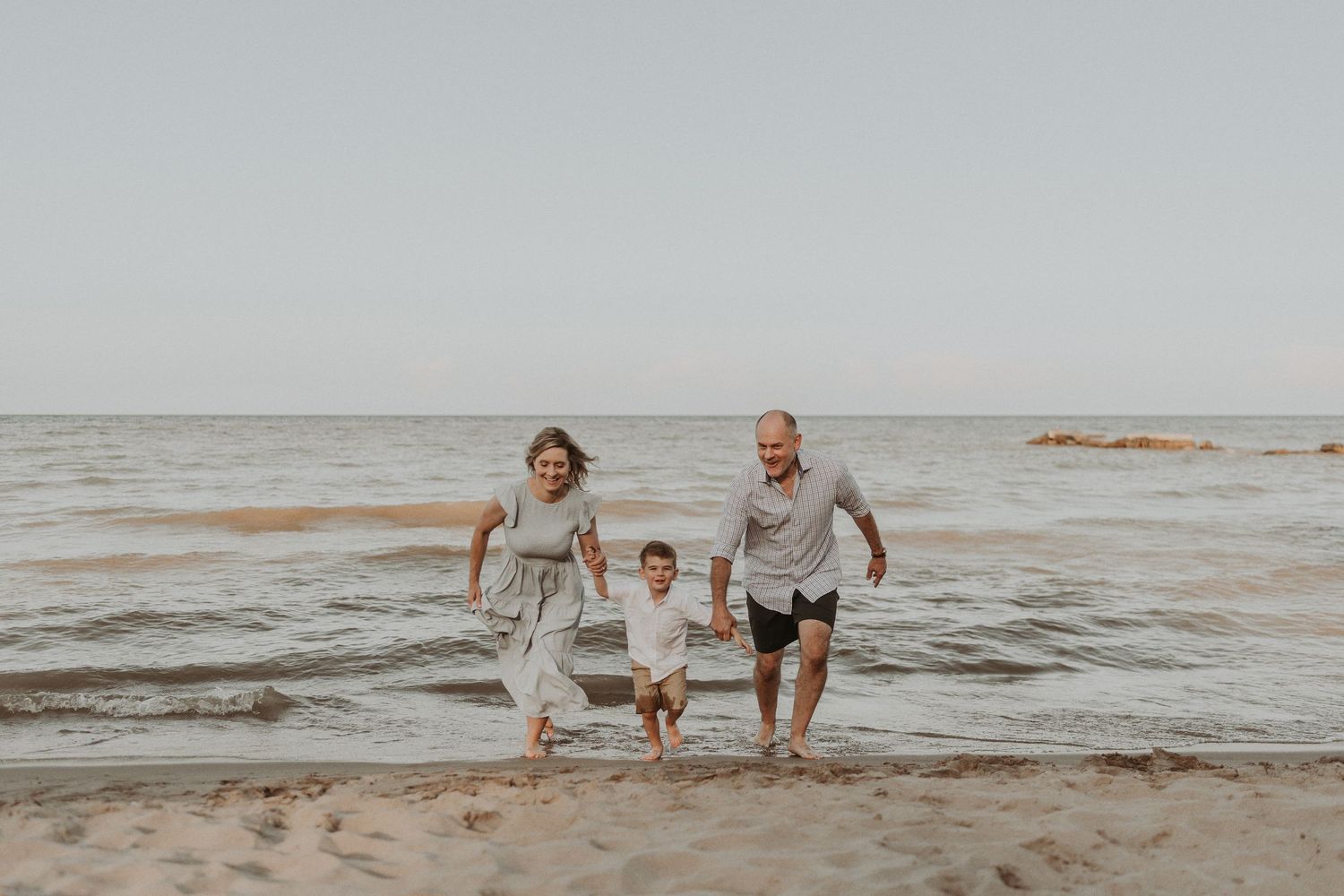 Family playing and splashing together in the ocean waves at the beach.